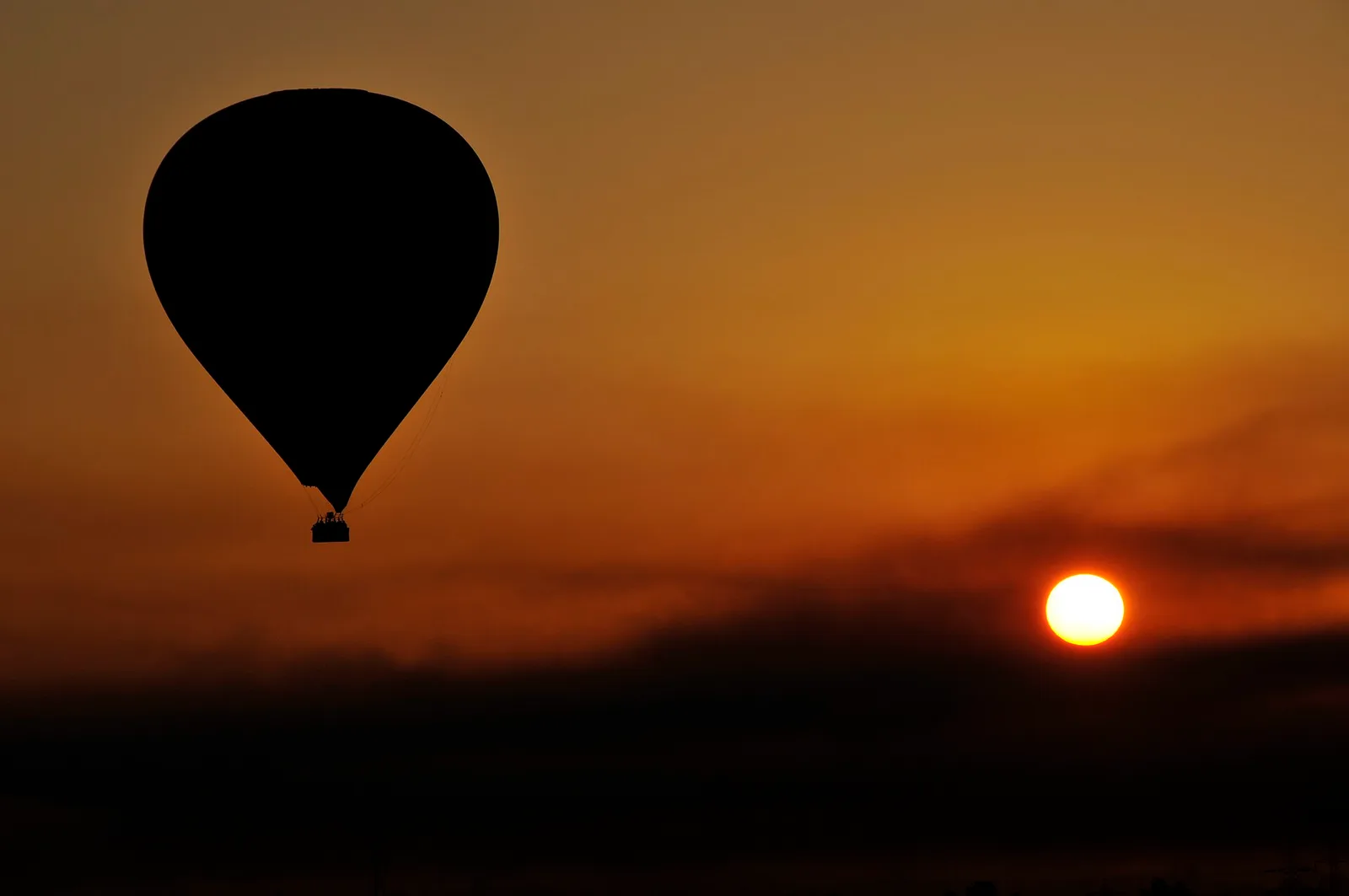 A hot-air balloon silhouetted against the sunrise over Luxor