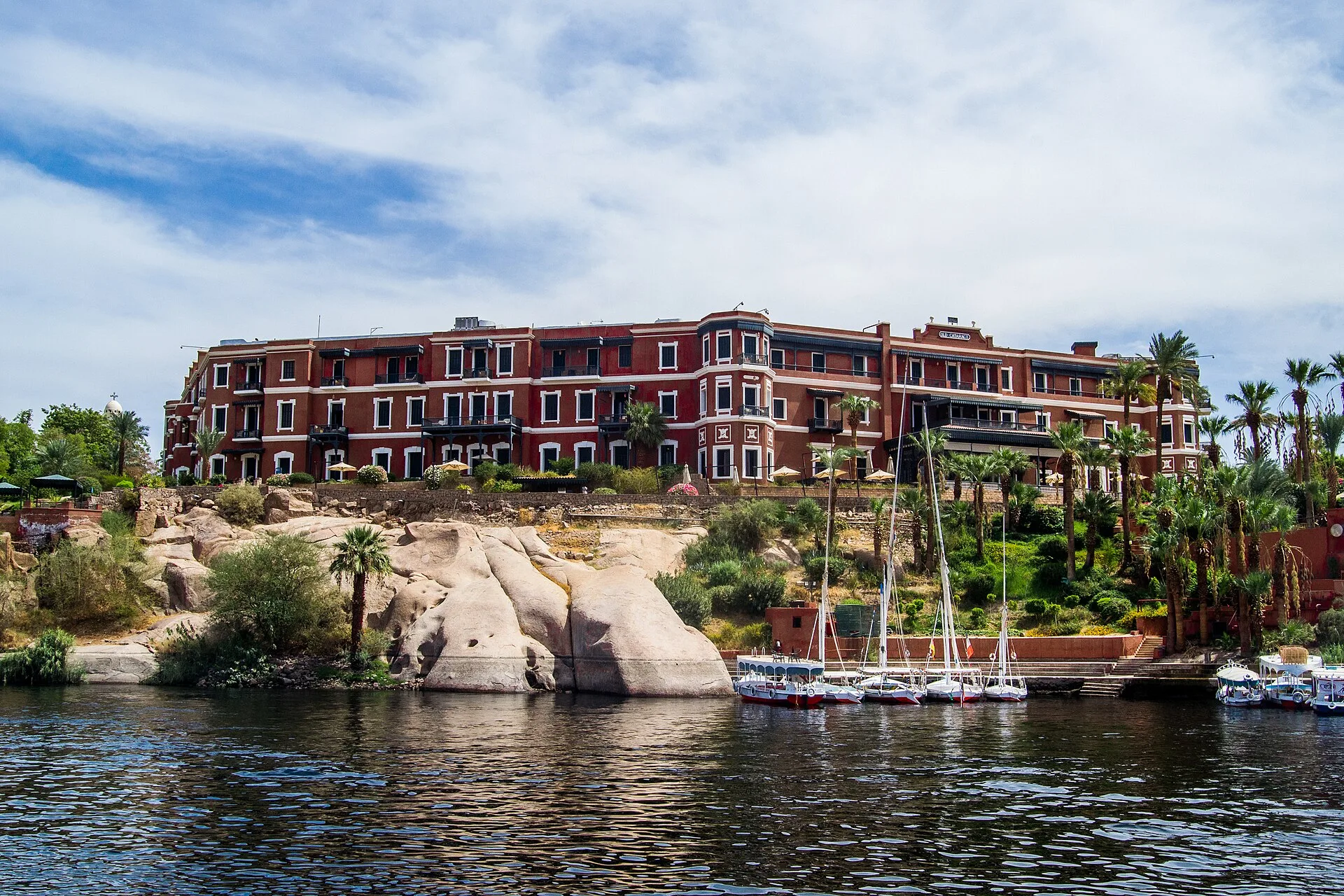 The red Victorian facade of the Old Cataract hotel above the Nile's granite rocks in Aswan