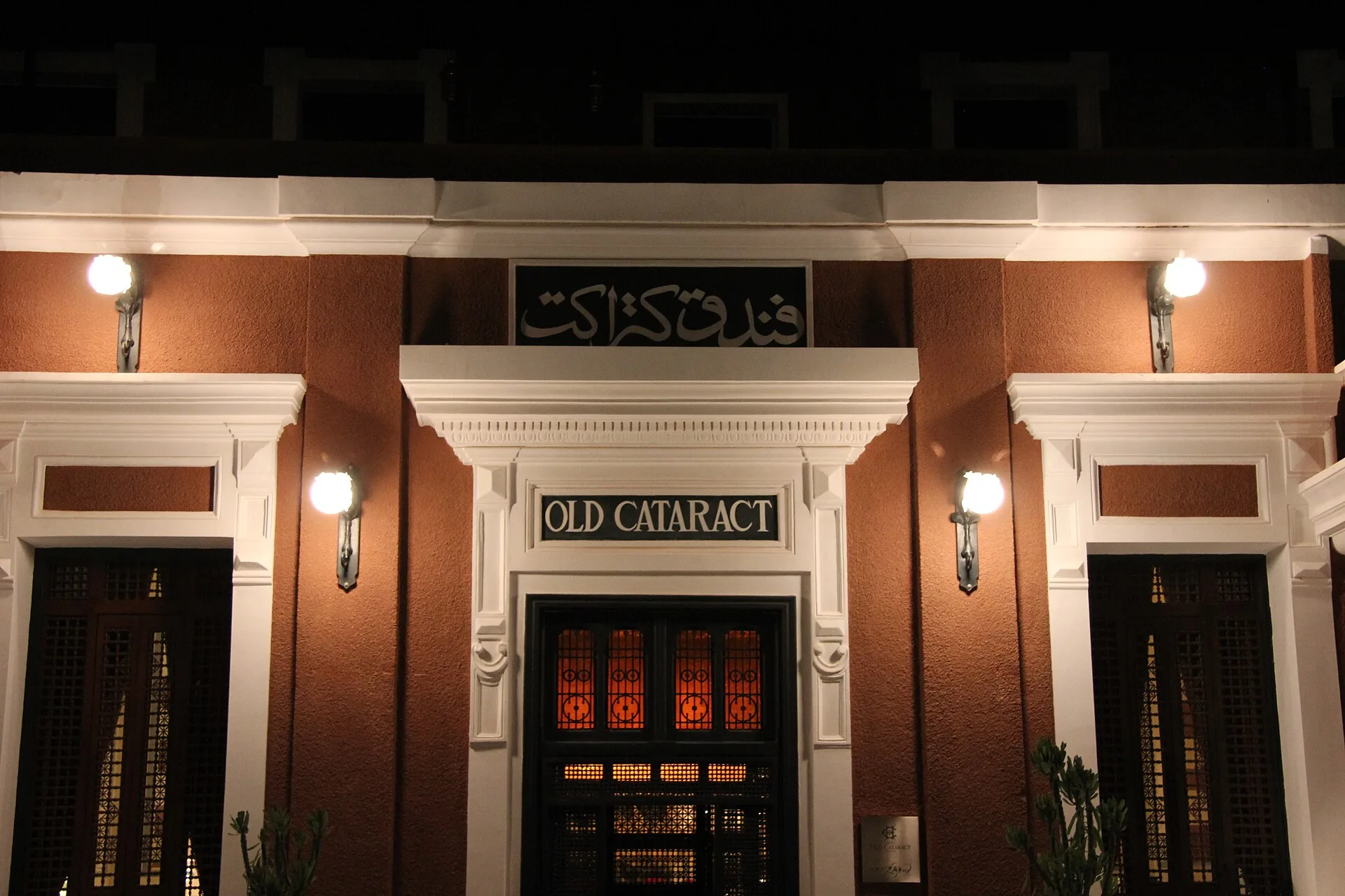 Illuminated entrance of the Old Cataract hotel with its bilingual name sign