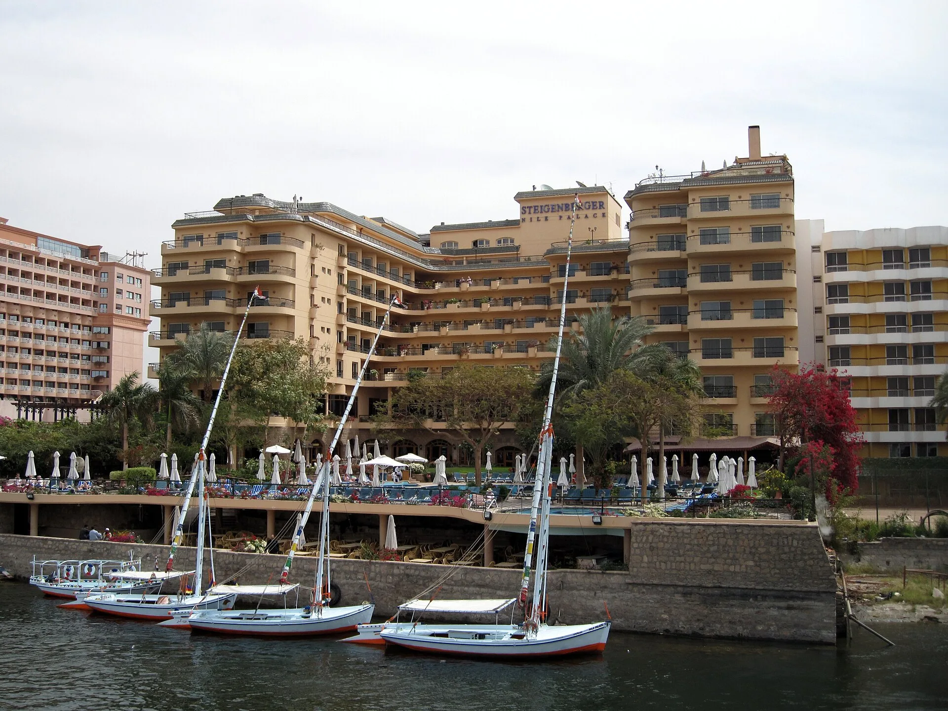 Steigenberger Nile Palace seen from the Nile, with feluccas moored below its pool terrace