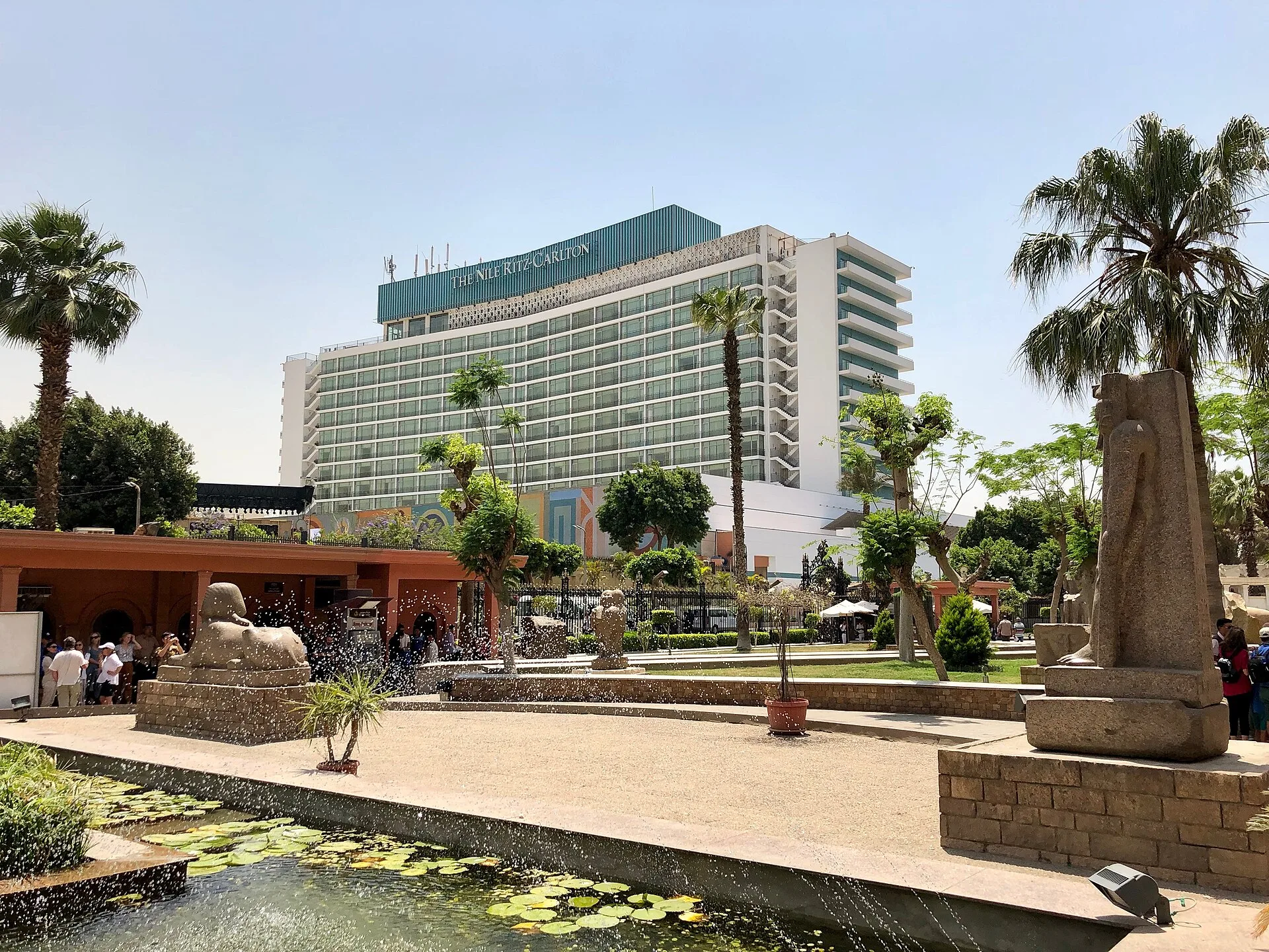 The Nile Ritz-Carlton tower seen from the Egyptian Museum garden, with palms and a lily pond in front